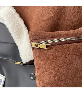 Detail of smooth gold zipper and texture on brown suede bag with white fleece lining