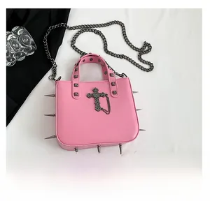Detailed view of pink punk handbag featuring metallic cross, studs, and spiked bottom edges