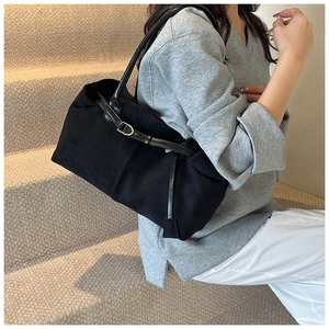 Macro detail of a black matte tote bag with polished straps and metallic buckle accents