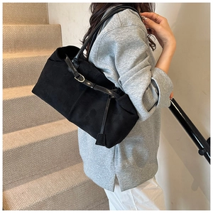 Detail of black matte tote bag with slim straps and metal buckle on indoor stairs