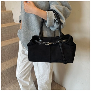 Model posing with a vintage black matte tote bag featuring glossy leather strap details