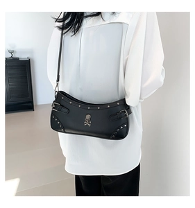 Detail of black PU crossbody bag with skull logo and silver studs on a white shirt