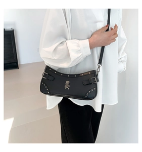 Detail of black punk shoulder bag featuring silver skull emblem and metal rivet trim