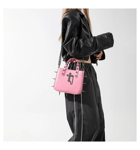 Detail of pink gothic handbag with silver metal cross and punk style stud decorations