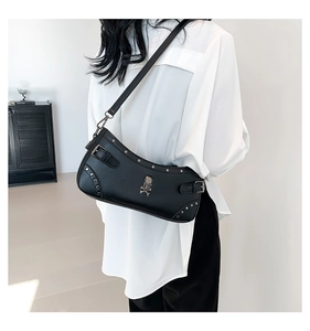 Detail of black PU leather crossbody bag with silver skull rivets and metal buckles