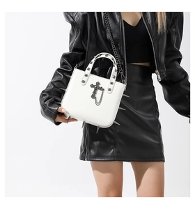 Detail of gothic white leather handbag with silver studs and cross pendant decoration