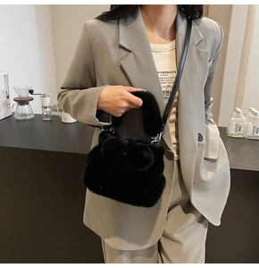 Détail du sac seau noir en fausse fourrure avec pompons et bandoulière en cuir