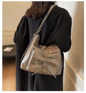 Detail der grauen Lackleder-Hobo-Tasche mit dekorativer Schleife und Reißverschluss