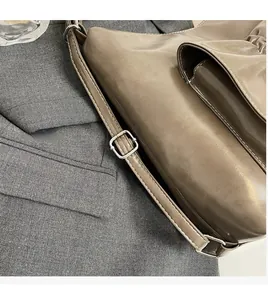 Detailansicht verstellbarer Schultergurt mit Metallschließe an brauner Tasche