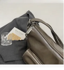Detailansicht des silbernen Metallreißverschlusses und weißer Nähte auf braunem Leder