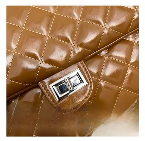 Close-up of silver metal twist lock on brown quilted leather bag with glossy finish
