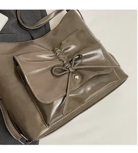 Detail der olivgrünen Ledertasche mit Schleifenstruktur und metallischer Druckknopftasche