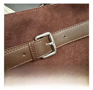 Close-up of premium silver buckle and smooth brown leather strap on suede tote bag