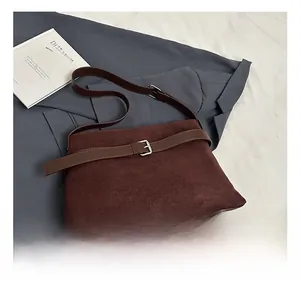 Close-up of vintage dark brown suede shoulder bag featuring buckle strap detail and texture