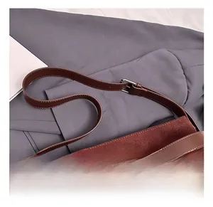 Detail of adjustable leather shoulder strap with silver metal buckle on a suede handbag