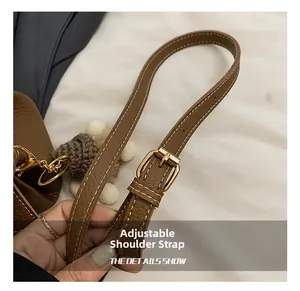 Détail de la bandoulière réglable en cuir marron avec boucle en métal doré et coutures