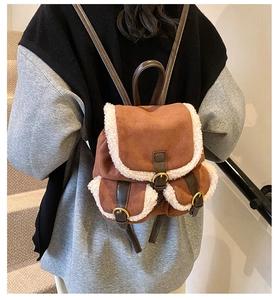 Close-up of brown suede mini backpack featuring white faux shearling trim and buckles