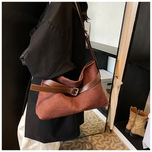 Détail du sac à bandoulière en daim bordeaux avec lanière en cuir brun et boucle métal