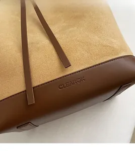 Macro detail of brown suede and smooth leather texture with stitched logo branding