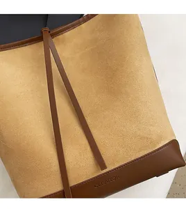 Macro detail of camel faux suede fabric and dark brown leather trim on a bucket bag