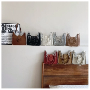 Detail of color-block crescent shoulder bag featuring braided edges and oversized buckle