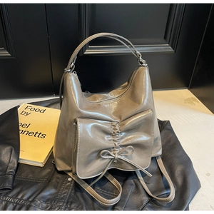 Detail of khaki leather bag featuring a decorative bow pocket and metallic hardware