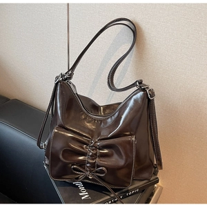Detail der dunkelbraunen Totebag aus Kunstleder mit großer Schleife und Glanzeffekt