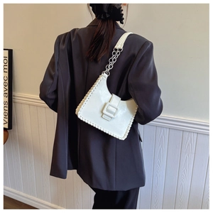 Detail of white glossy leather shoulder bag with woven edges and silver chain strap