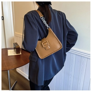 Close-up of caramel hobo bag featuring woven edges and large square leather buckle detail