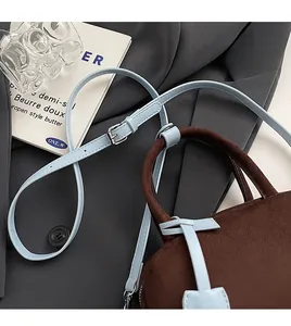 Detail of adjustable blue leather shoulder strap with silver buckle on brown suede bag