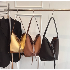 Three large suede tote bags in beige, brown, and black hanging on a metal rack for work