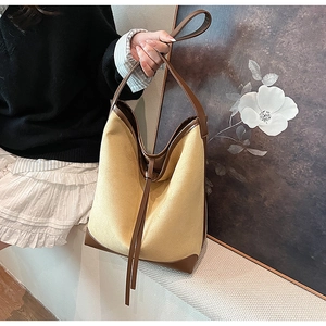 Close-up of contrast leather stitching and textured yellow suede on bucket bag