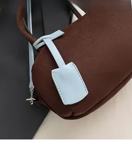 Close-up of deep brown suede texture with a contrasting light blue leather tag detail