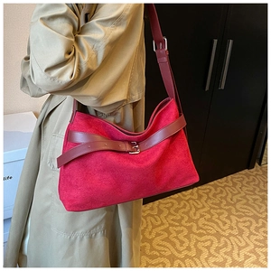 Gros plan sur le sac fourre-tout en daim rouge avec bandoulière et boucle métallique