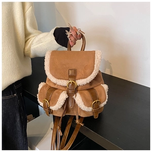 Detail of faux fur trim on a brown suede bucket backpack with vintage gold buckles