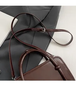 Detail of dark brown vintage handbag with adjustable shoulder strap and silver buckle