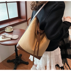 Side view of a vintage khaki suede bucket bag with brown leather trim and tassel detailing