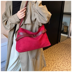 Detail of red matte suede half-moon shoulder bag with retro leather belt and metal buckle