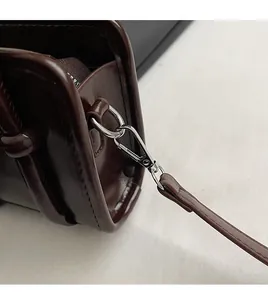 Detailed close-up of detachable silver metal swivel hook and strap loop on leather handbag