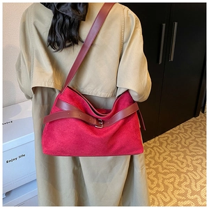 Détail d'un sac cabas en daim rouge porté sur un manteau beige pour un look élégant