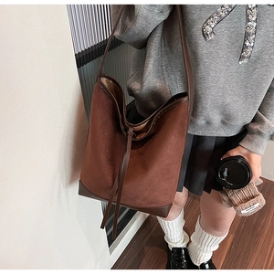 Close-up of large dark brown suede bucket bag with long leather drawstring detail