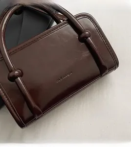 Detail of embossed logo on dark brown leather Boston bag with round top handles