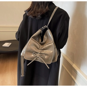 Detail of grey glossy tote bag with bow accent and pleated design on shoulder strap