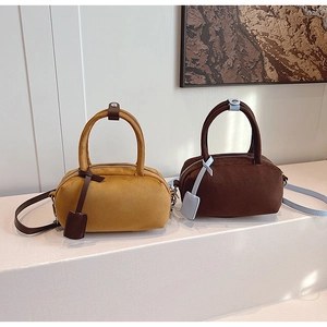 Close-up of yellow and brown frosted leather cylinder bags with dual handles and straps