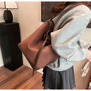 Detail of vintage brown suede tote bag with leather strap shown in a lifestyle setting