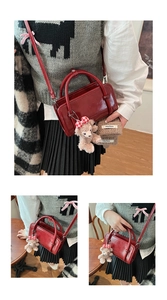 Detail of red glossy patent leather handbag with a cute brown plush bear charm