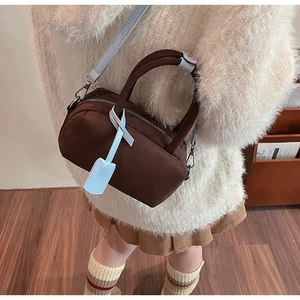 Detail of dark brown suede pillow bag with light blue shoulder strap and metal zipper