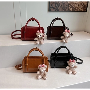 Detail view of four stylish faux leather bags in red, brown, tan and black with bear charms