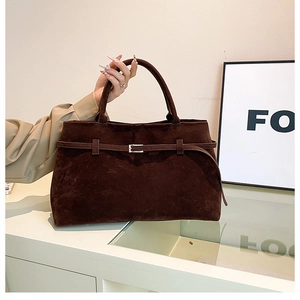 Detail of dark brown suede tote bag with slim decorative strap and silver buckle handle
