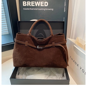 Detailed macro of brown suede tote bag with decorative strap and metallic buckle
